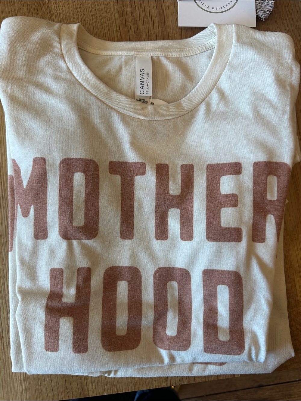 Bella Canvas Cream Tee with rust colored 'MOTHERHOOD' Graphic